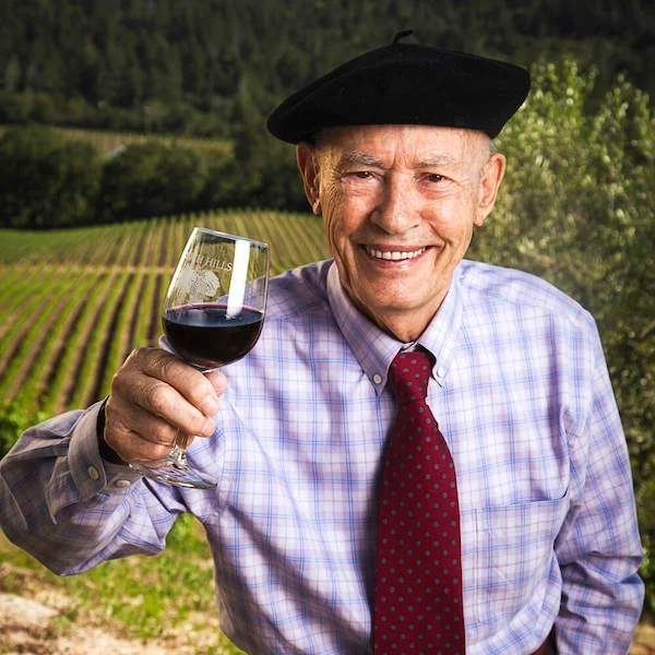 mike grgich in front of vineyard holding wine glass cheersing