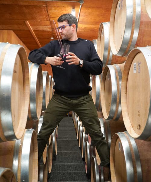 sebastian standing on barrels with a wine glass in hand