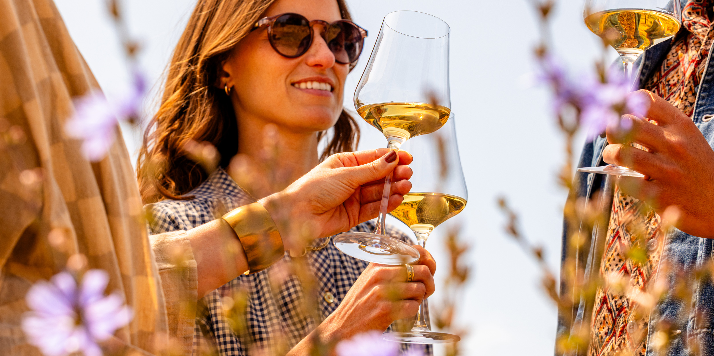 A trio of friends toast with Napa Valley white wine in a scenic meadow.