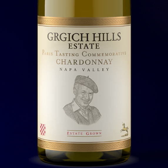 Label of Grgich Hills Estate Paris Tasting Commemorative Chardonnay, honoring the Judgement of Paris in 1976. The bottle's label is set in front of a royal blue background.