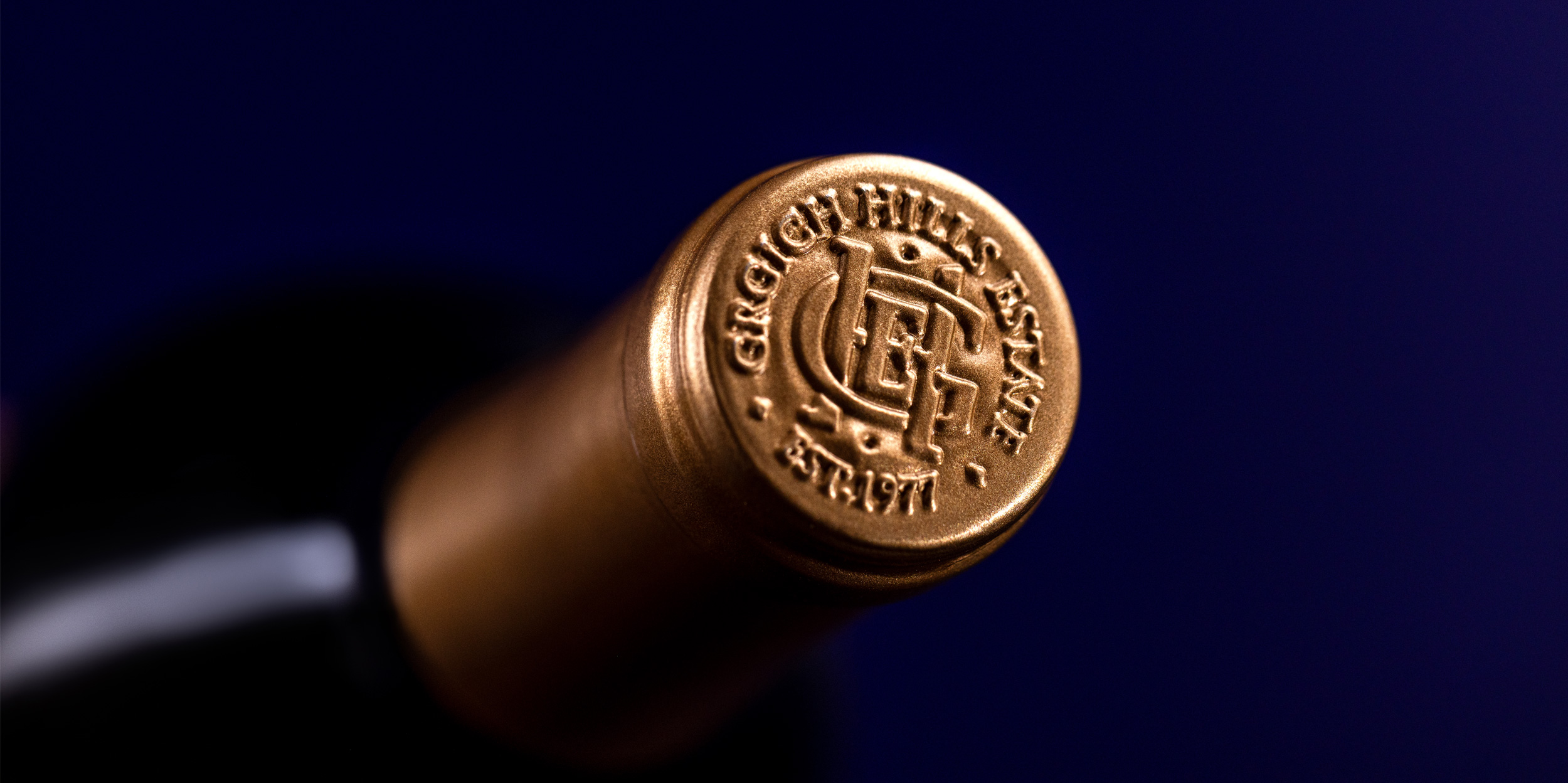 The embossed, golden top of the foil capsule on a bottle of Paradise Block Cabernet Sauvignon. It bears the logo of Grgich Hills Estate, established in Napa Valley in 1977.