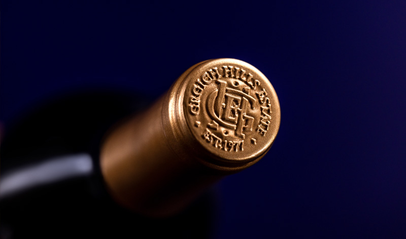 The embossed, golden top of the foil capsule on a bottle of Paradise Block Cabernet Sauvignon. It bears the logo of Grgich Hills Estate, established in Napa Valley in 1977.